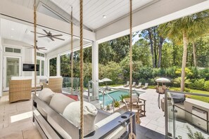 A modern outdoor living area with a pool, seating, and a view of the surrounding greenery.