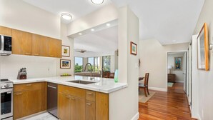 Una cocina moderna con armarios de madera, horno empotrado y una isla grande con pileta.