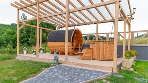 A wooden structure with a covered patio area, a barrel-shaped building, and a statue of a donkey. - Cottage in Duszniki Zdroj With Ski & Spa (Szczytna)