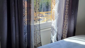 A bedroom with a bed, curtains, and a view of a construction site outside. - Large suite with access to living room, terrace, garden - Thiers center, train station (Thiers)