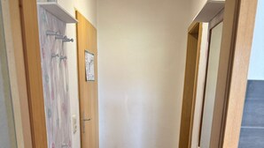A narrow hallway with wooden flooring, a metal rack, and wooden doors. - Apartment Blueberry Pool Sauna Netflix WIFI (Zwiesel)