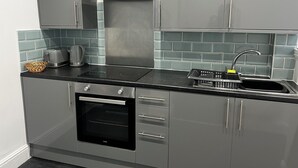 Cozinha moderna com eletrodomésticos de aço inoxidável, forno embutido e pia com torneira.