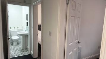Una habitación de hotel con baño, cama y puerta.