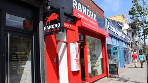 Fachada de loja com exterior vermelho e letreiros para 'RANCHO Steak House & Sushi Bar'.