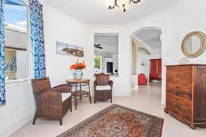 Un salon spacieux agrémenté d’un grand tapis, de meubles en osier, d’une armoire en bois et offrant une vue sur une autre pièce, accessible par une arche.
