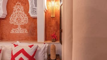 A room with a decorative wall, a hanging light fixture, and a small table with a vase.