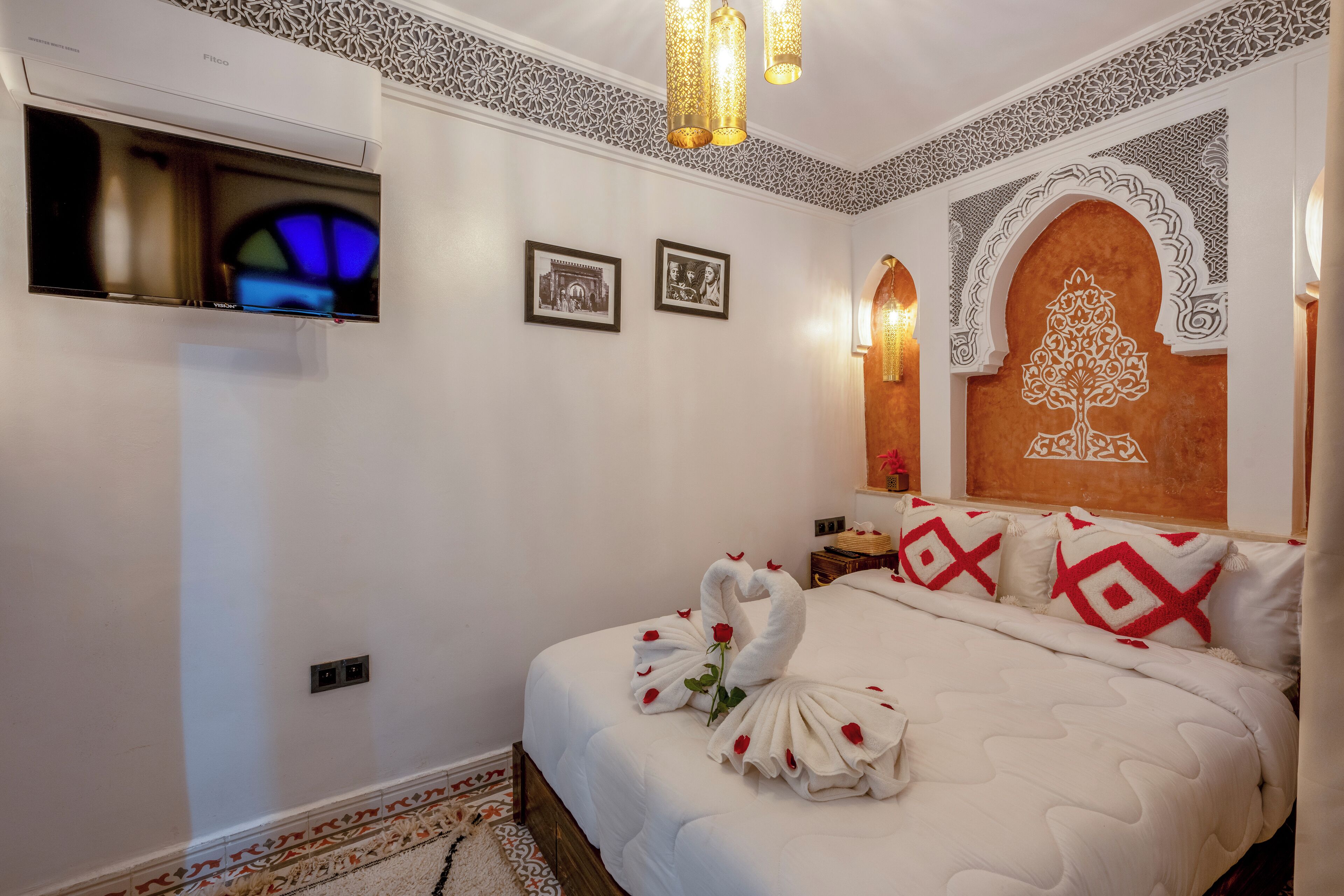 Quarto de hotel com uma cama grande, televisão de tela plana na parede e arte decorativa na parede.