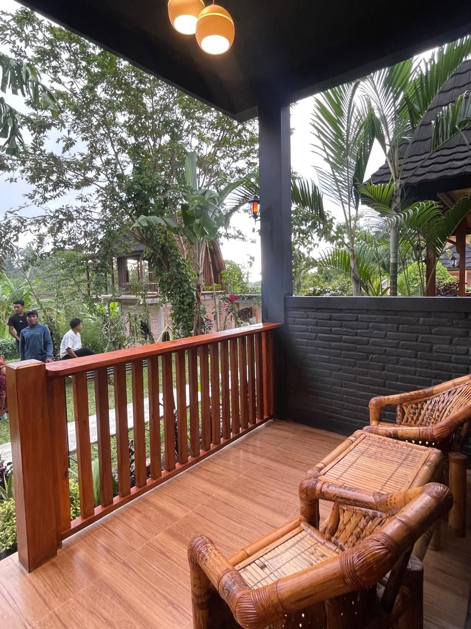 A wooden deck with a railing, wicker furniture, and a view of the surrounding greenery.