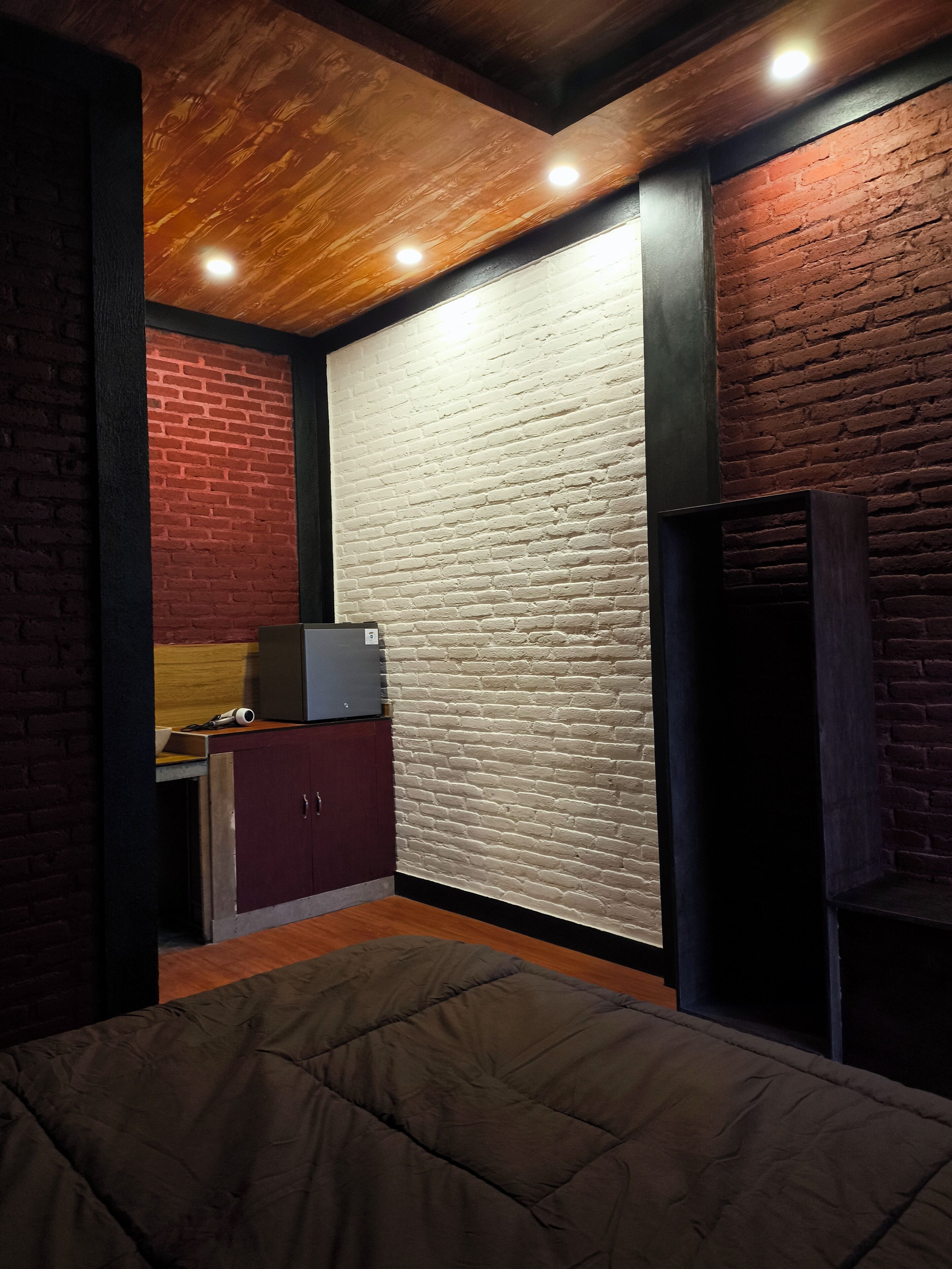 Una habitación con cama, kitchenette y pared de ladrillo.