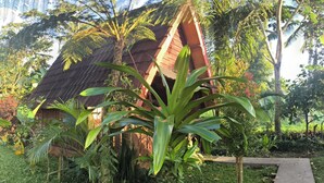 A traditional thatched-roof house surrounded by lush greenery and a clear sky. - Tetebatu Valley Bungalows  (Tetebatu)