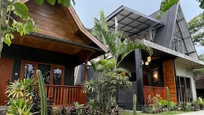 A modern house with a wooden porch, a metal roof, and a well-maintained garden with various plants. - Tetebatu Valley Bungalows  (Tetebatu)
