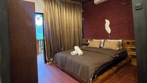 A bedroom with a wooden ceiling, a bed with a dark bedspread, a ceiling fan, and an air conditioning unit on the wall. - Tetebatu Valley Bungalows  (Tetebatu)