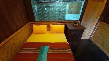 A wooden room with a bed, a small table, and a window.