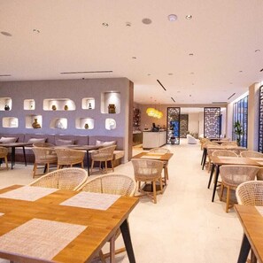 A modern interior with wicker furniture, recessed lighting, and a central dining area. - Tris3 Hotel (Orikum)