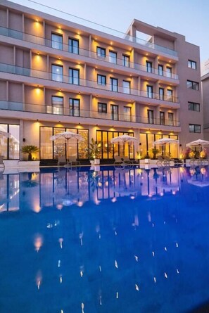 A multi-story hotel with a swimming pool, outdoor seating, and a well-lit facade. - Tris3 Hotel (Orikum)