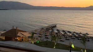 Ein Strandhotel mit Poolbereich, Sonnenschirmen und Liegestühlen.