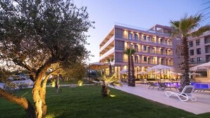 Ein Hotel mit Poolbereich, Sitzgelegenheiten im Freien und einem gepflegten Rasen.