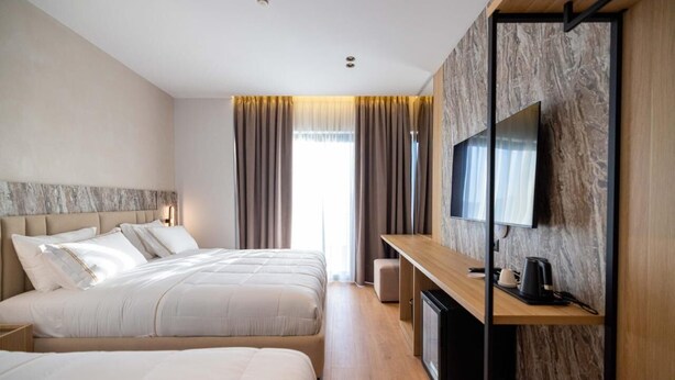 Ein Hotelzimmer mit zwei Betten, einem Fernseher, einer Kaffeemaschine und einem Schreibtisch.