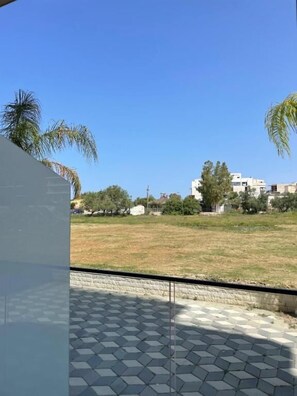 A view of a residential area with a paved patio, palm trees, and buildings in the background. - Tris3 Hotel (Orikum)