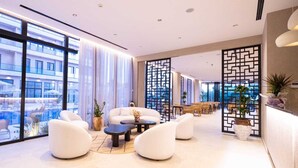 Eine moderne Hotellobby mit Sitzgelegenheiten, großen Fenstern und Blick auf den Pool.