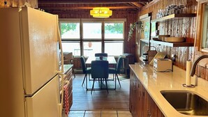 Une cuisine dotée de meubles en bois, d’un réfrigérateur, d’un coin repas avec une table et des chaises, et d’une fenêtre donnant sur l’extérieur.