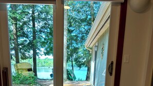 Une chambre dotée d’un grand lit et d’une porte-fenêtre coulissante donnant sur une terrasse en bois qui offre une vue sur un lac.