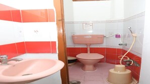 Un baño pequeño con un lavamanos rosa, inodoro y bidé.