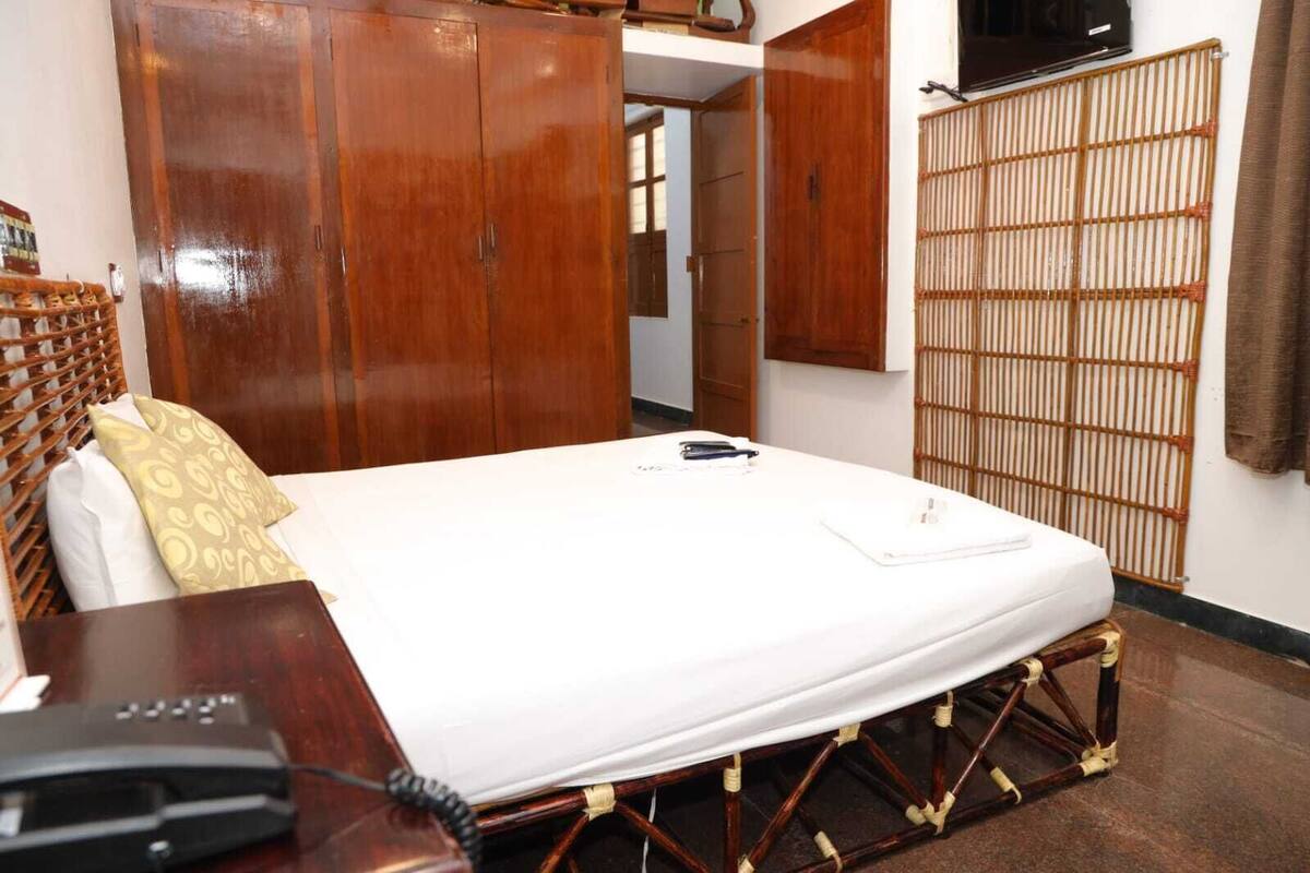 A hotel room with a bed, a desk with a telephone, and a wardrobe.