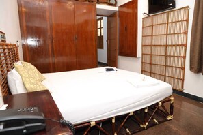 A hotel room with a bed, a desk with a telephone, and a wardrobe. - LA VILLA CREOLE (Puducherry)