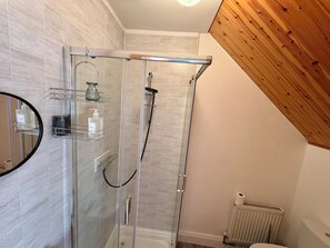 Un baño moderno con cabina de ducha de vidrio, techo de madera y pared de azulejos.
