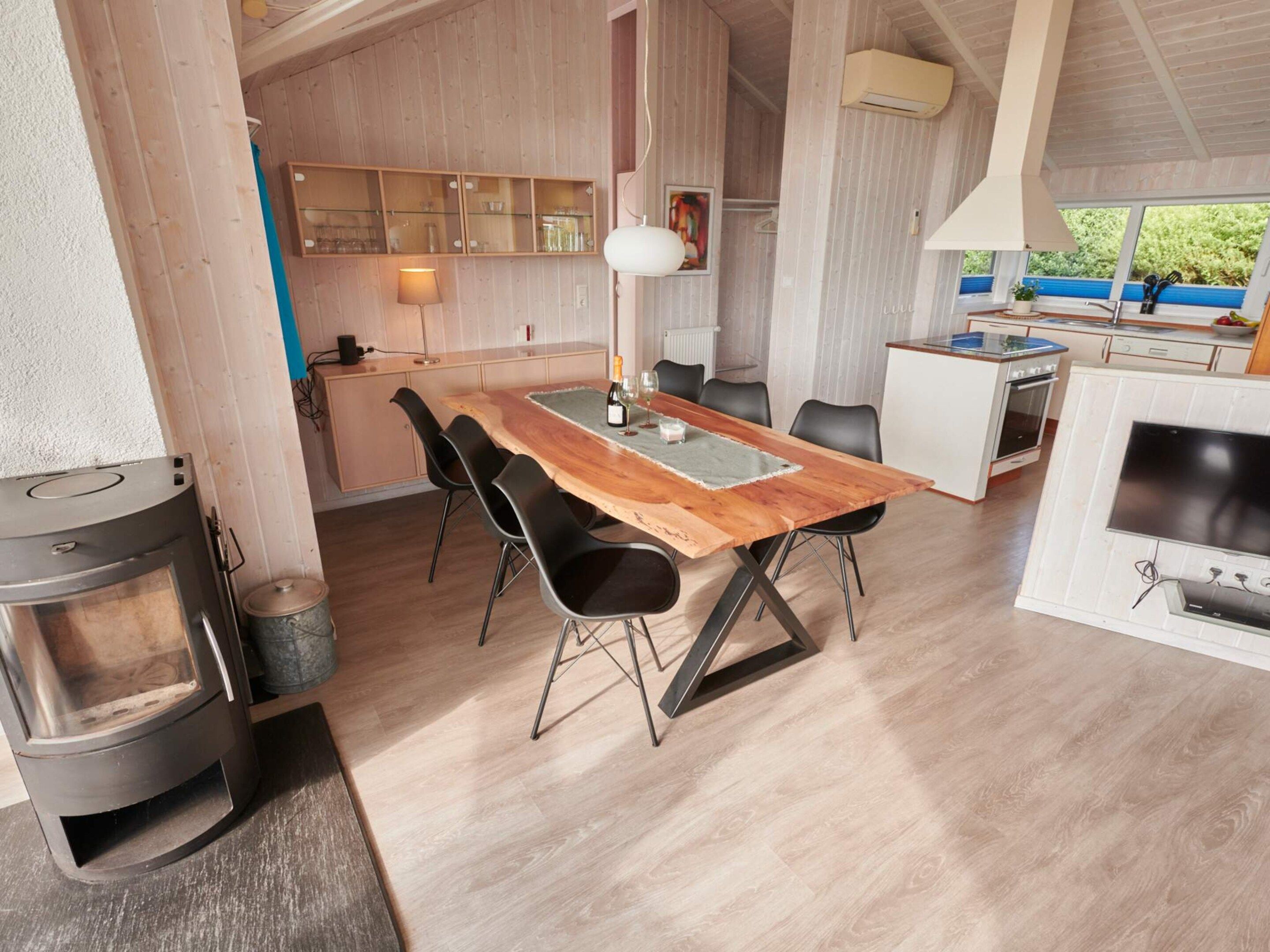 Una cocina moderna con una mesa de comedor de madera, sillas negras y una estufa empotrada.