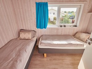 A small room with two beds, a window with curtains, and a view of the outside. - 4 Star Holiday Home in Friedrichkoog (Friedrichskoog)