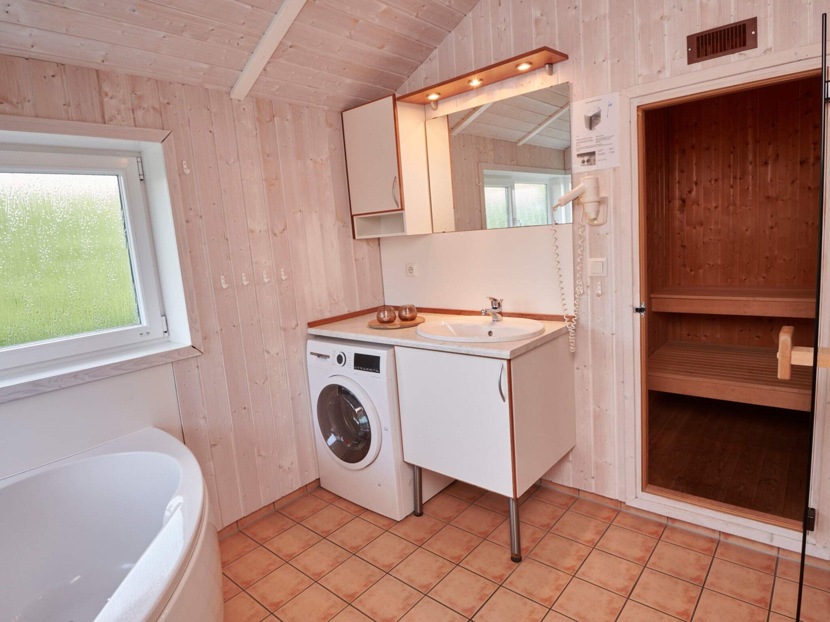A compact bathroom with a washing machine, a sink, and a large mirror.