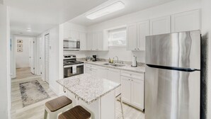 Een moderne keuken met witte kasten, roestvrijstalen apparatuur en een granieten aanrecht.