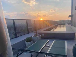 Eine Dachterrasse mit Pool, Glasgeländern und Kübelpflanzen.