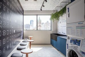 Een modern kantoor met uitzicht op de stad, een groot raam, een whiteboard met symbolen en een wasmachine.