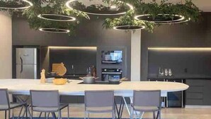 Een moderne keuken met een centraal eiland, barstoelen en ronde verlichting boven.