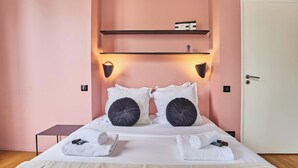 A neatly made bed with white linens and two black decorative pillows, a bedside table with a lamp, and a shelf above the bed. - Air-conditioned Apartment in the Center of Paris (Paris)