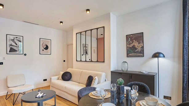 A modern living room with a sofa, coffee table, and dining table set for four. - Air-conditioned Apartment in the Center of Paris (Paris)