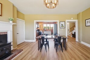 A dining area with a wooden table and chairs, a fireplace, and a view into the kitchen. - NEW! Peaceful Retreat with Scenic Surroundings (Martinsburg)