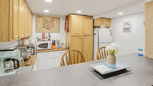 Una cocina compacta con armarios de madera, un microondas, un refrigerador y una zona de comedor con una mesa y sillas.