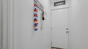 Un pasillo con una puerta blanca, un letrero en la pared y una guirnalda decorativa.