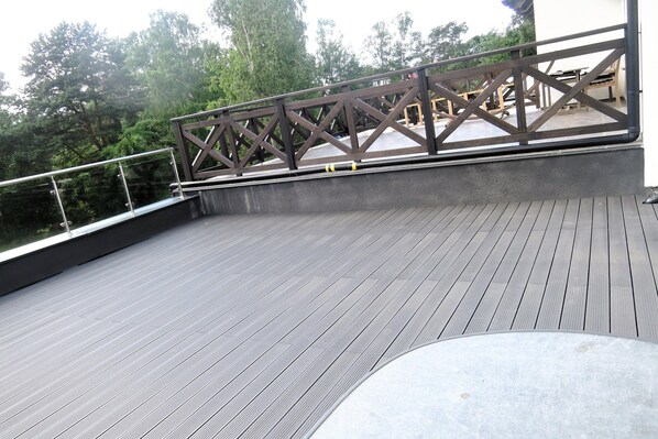 A wooden deck with a railing, surrounded by trees.
