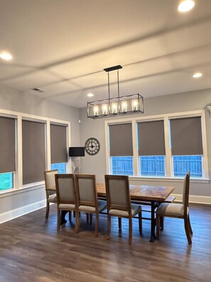 A dining area with a rectangular table and six chairs, a wall-mounted clock, and a ceiling light fixture. - Beautiful Escape, Mins from Carowinds & Lake Wylie (Charlotte)