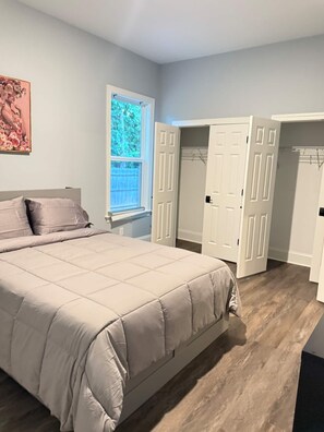 A bedroom with a bed, a window, and a walk-in closet.