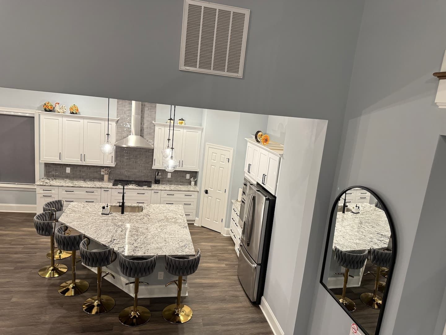 A modern kitchen with white cabinets, a granite countertop, stainless steel appliances, and a central island with bar stools.