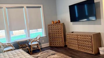Une chambre à coucher comprenant un lit, une télévision, une commode et une fenêtre avec des stores.
