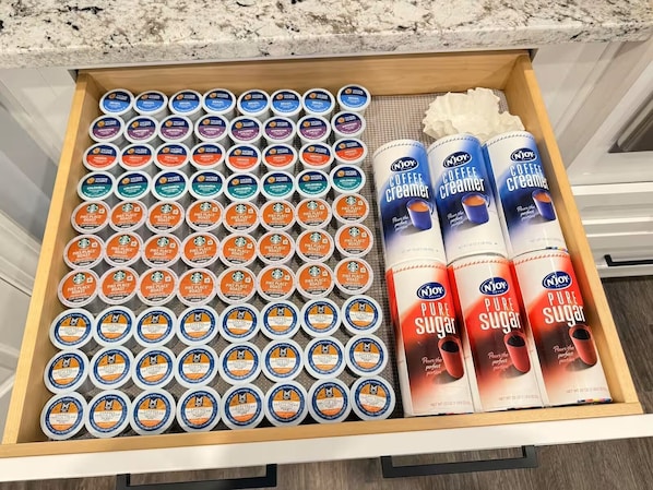 A drawer containing various coffee creamer containers and sugar packets.