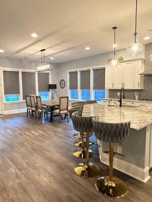 A modern kitchen with a marble island, bar stools, and pendant lighting.