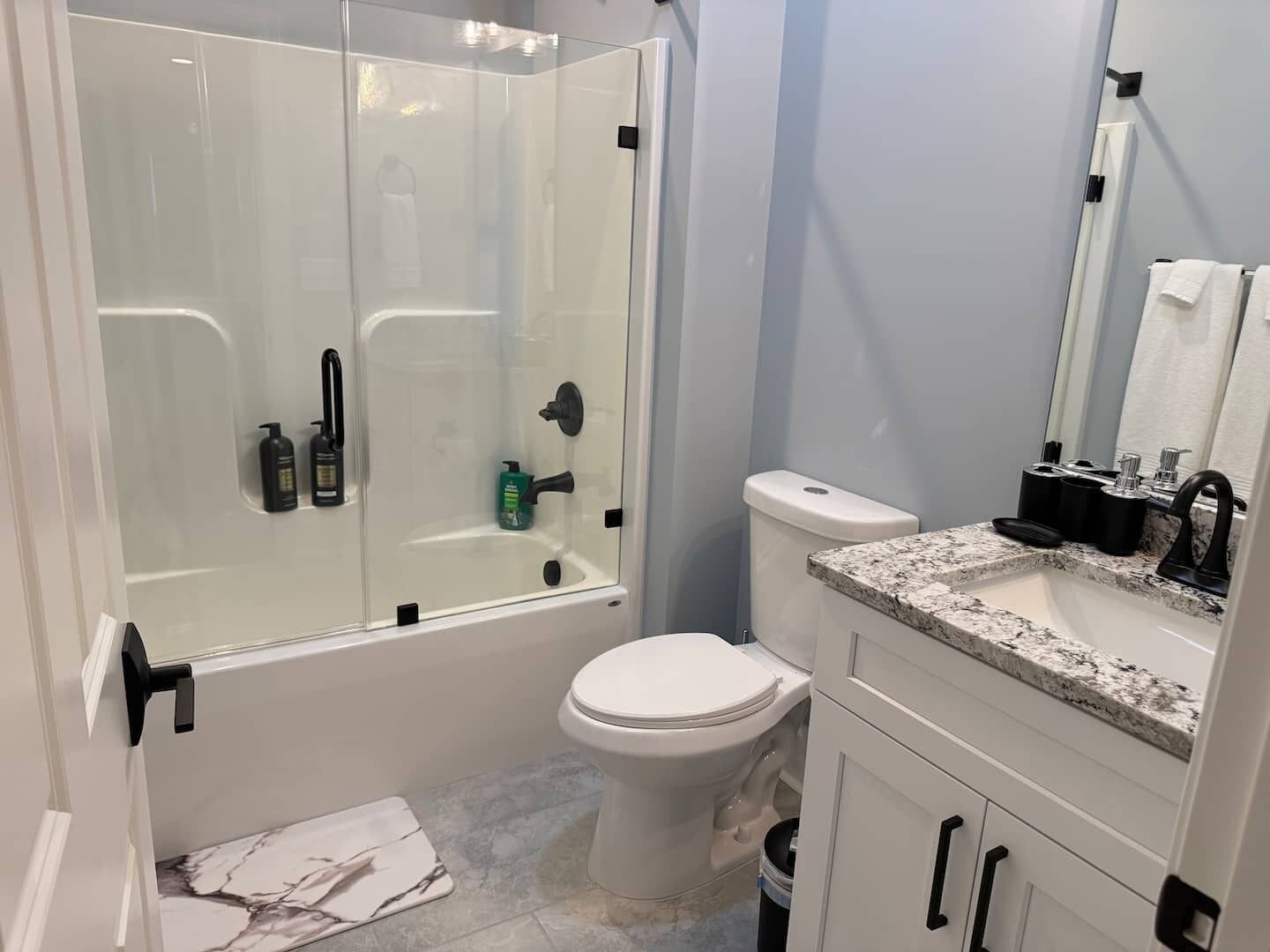 Une salle de bain moderne avec une douche à parois de verre, des toilettes et un lavabo doté d’un plan de travail en marbre.